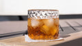 Whiskey glass with ice on a wooden surface with a blurred background
